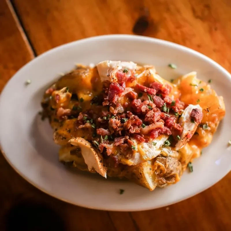 Close-up of a loaded baked potato with cheese, bacon, chicken, and herbs.