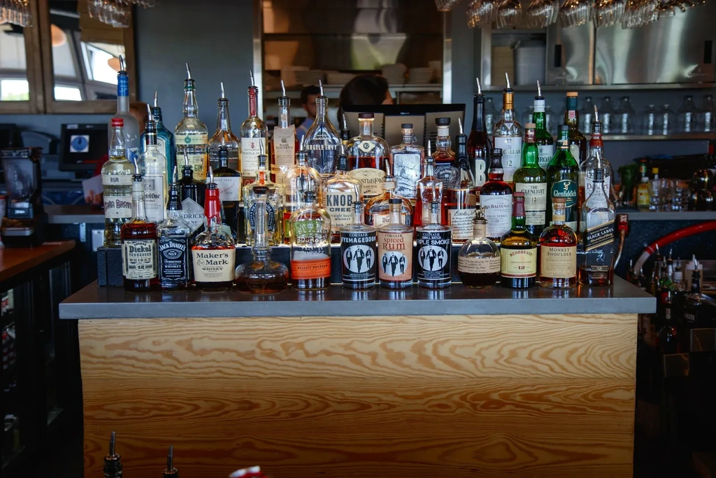 Well-stocked bar counter with various spirits bottles and hanging glasses.