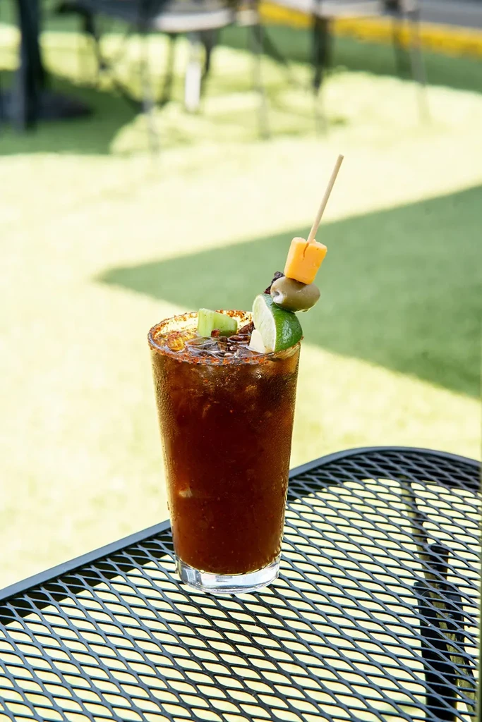 Spice-rimmed Bloody Mary or Michelada with cheese, olive, and lime.