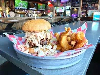 Fried chicken sandwich with coleslaw and fries on a checkered tray.