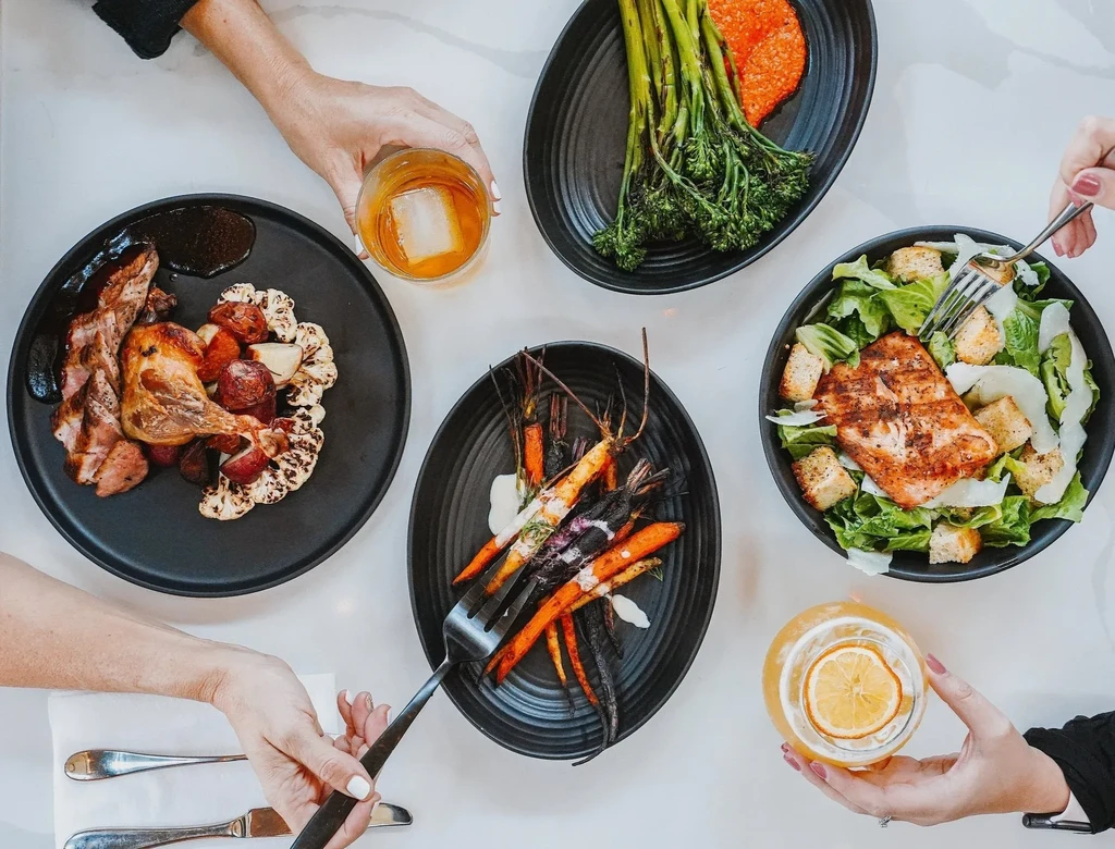 Overhead shot of elegant dining table with four gourmet dishes and drinks.