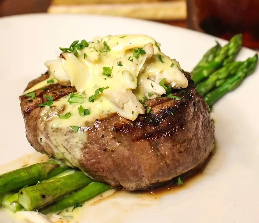Seared steak with creamy herb and crab sauce, asparagus.