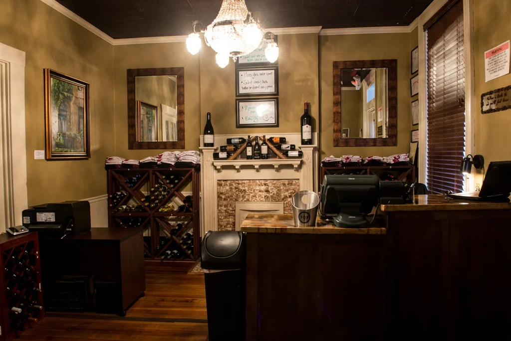 Warm, rustic wine bar interior with fireplace, chandelier, and wine racks.