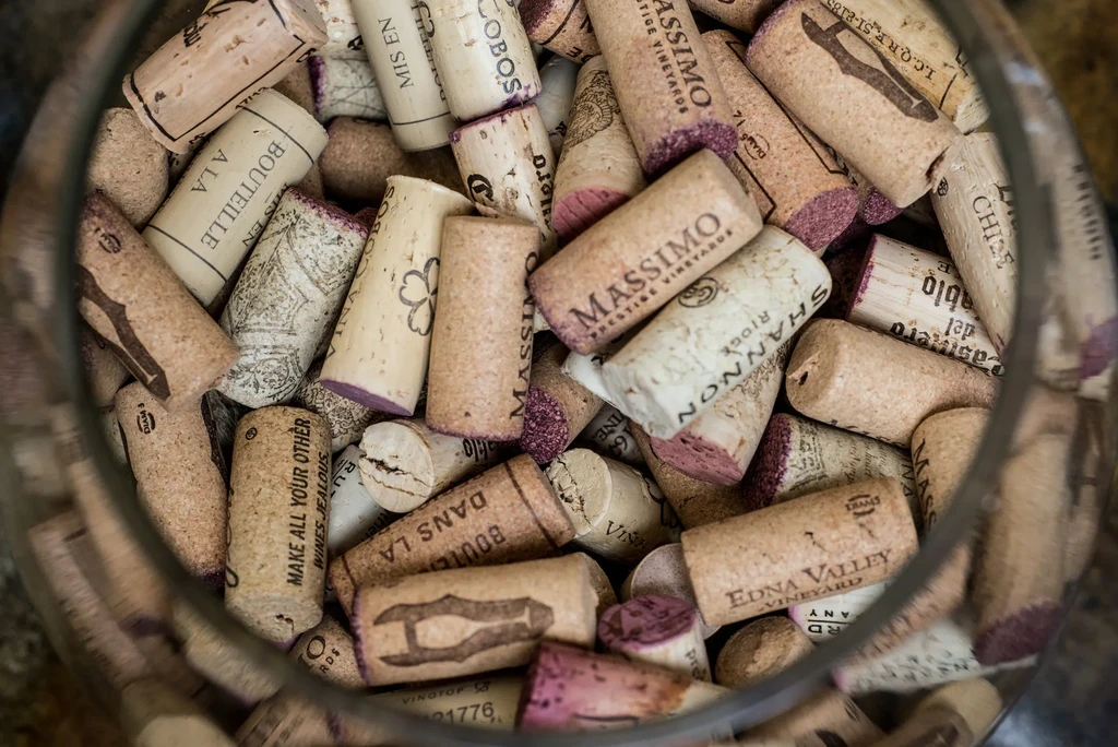 Close-up of used wine corks with labels, densely packed in glass.
