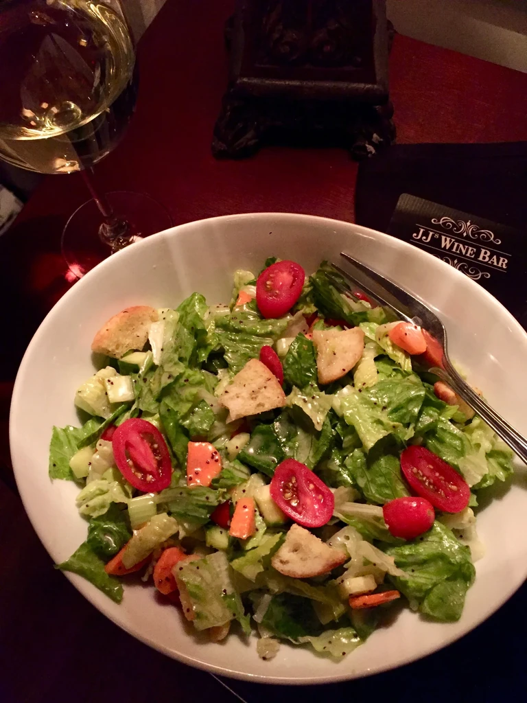 Overhead view of a salad with wine at JJ Wine Bar.