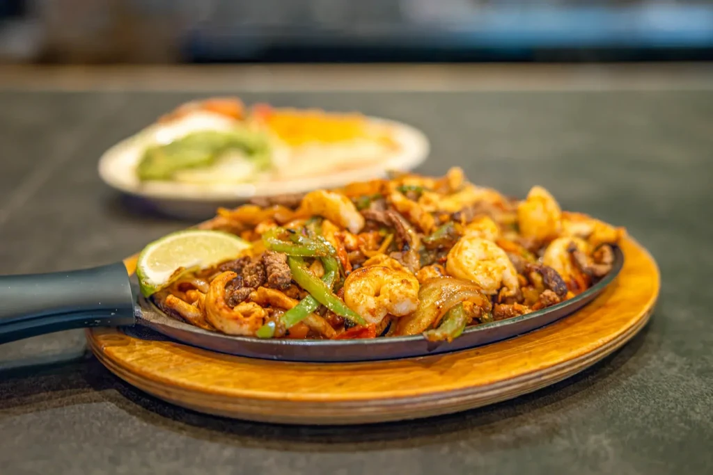 Sizzling fajita platter with shrimp, beef, bell peppers, and onions.