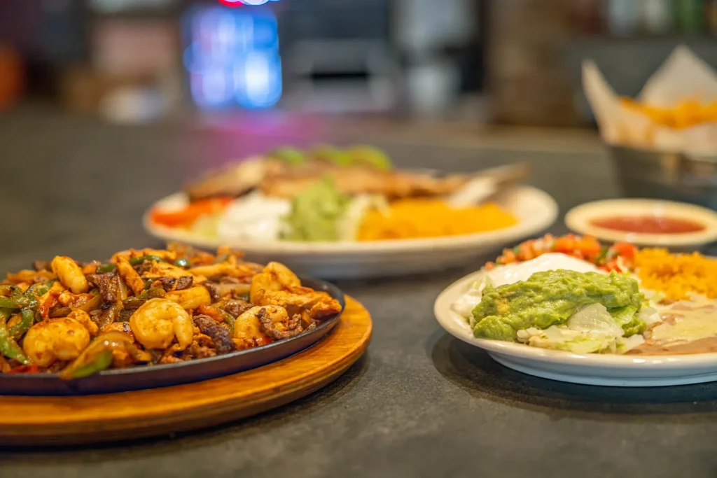 Close-up of Mexican food plates, with sizzling fajitas and guacamole.