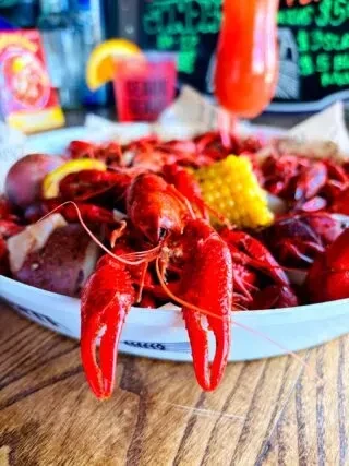 Bright red crawfish boil with potatoes, corn, and lemon slices.