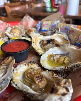 Seasoned oysters in shells, cocktail sauce, lemon, and Lance crackers.