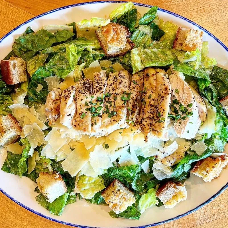 Well-presented chicken Caesar salad with grilled chicken, croutons, Parmesan.