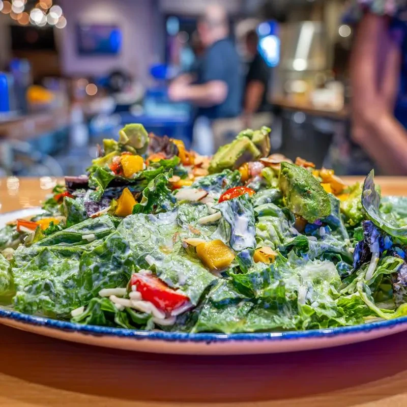 Close-up of a colorful salad with avocado, peppers, and almonds.