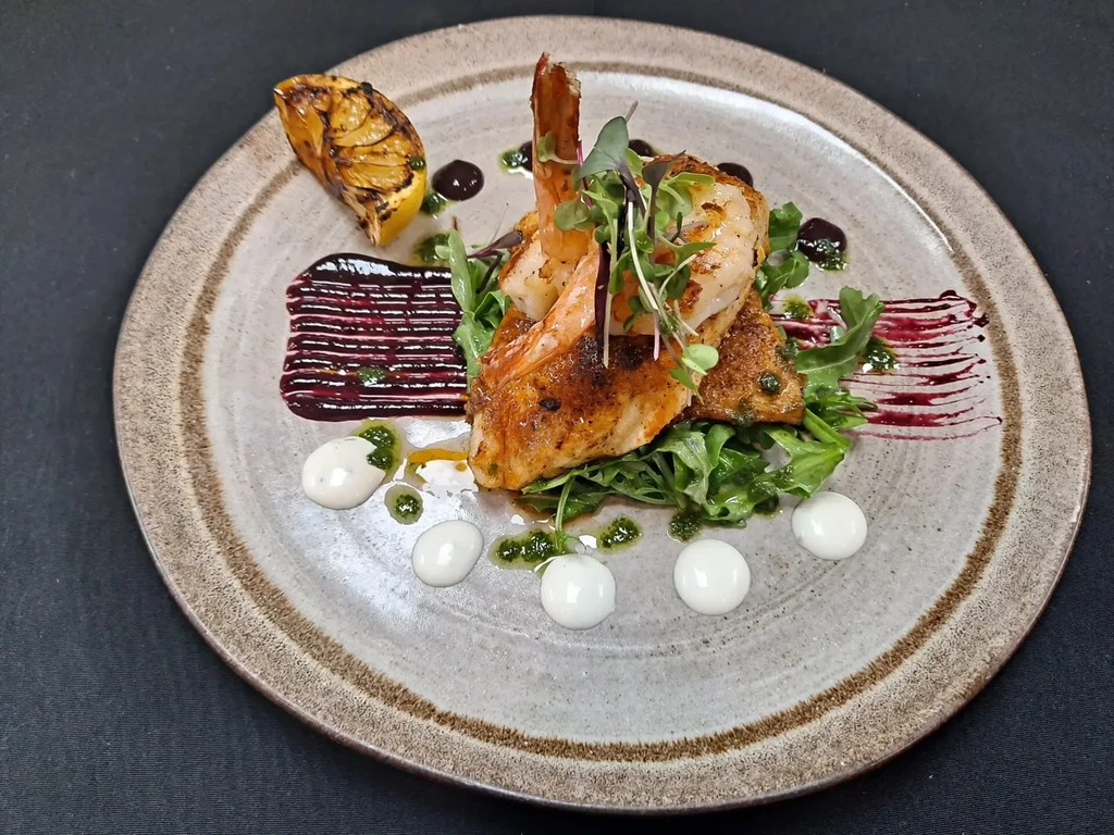 Seared fish and shrimp on greens with sauces and grilled lemon.