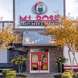 Modern ML ROSE restaurant exterior with red doors, owl logo, autumn trees.