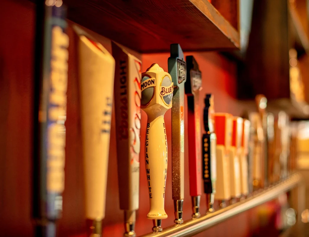 Beer tap handles on a bar, including Coors Light and Blue Moon.