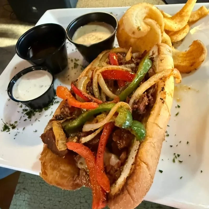 Generously filled sub sandwich, curly fries, and two distinct dipping sauces.