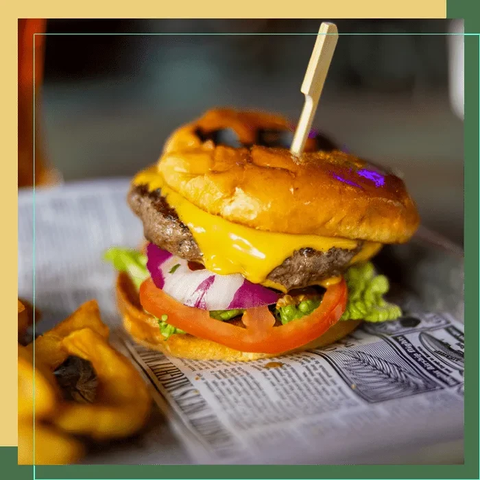 Gourmet hamburger with melted cheese, lettuce, tomato, onion, and fries.