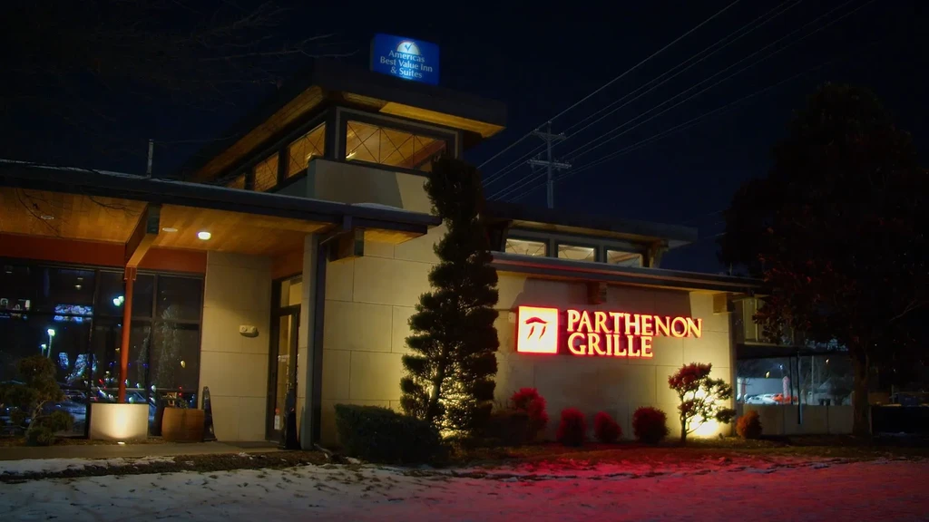 Illuminated modern building for Parthenon Grille restaurant and hotel at night.