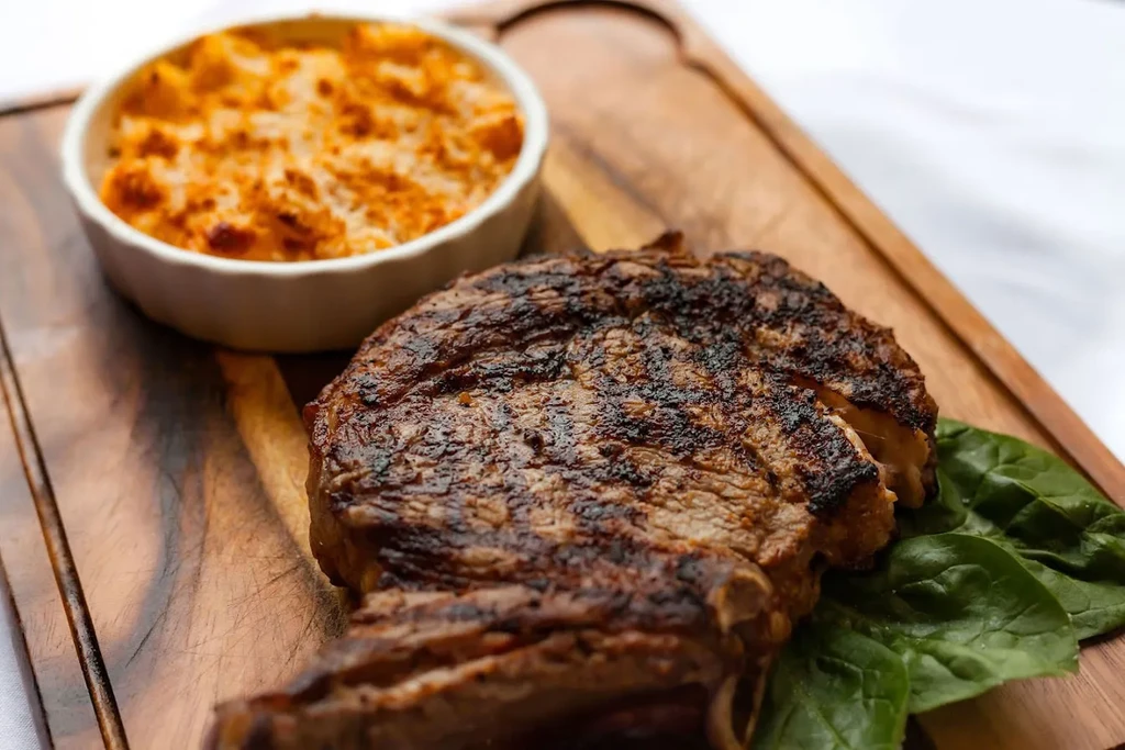 Thick grilled steak with grill marks, mac and cheese, and spinach.