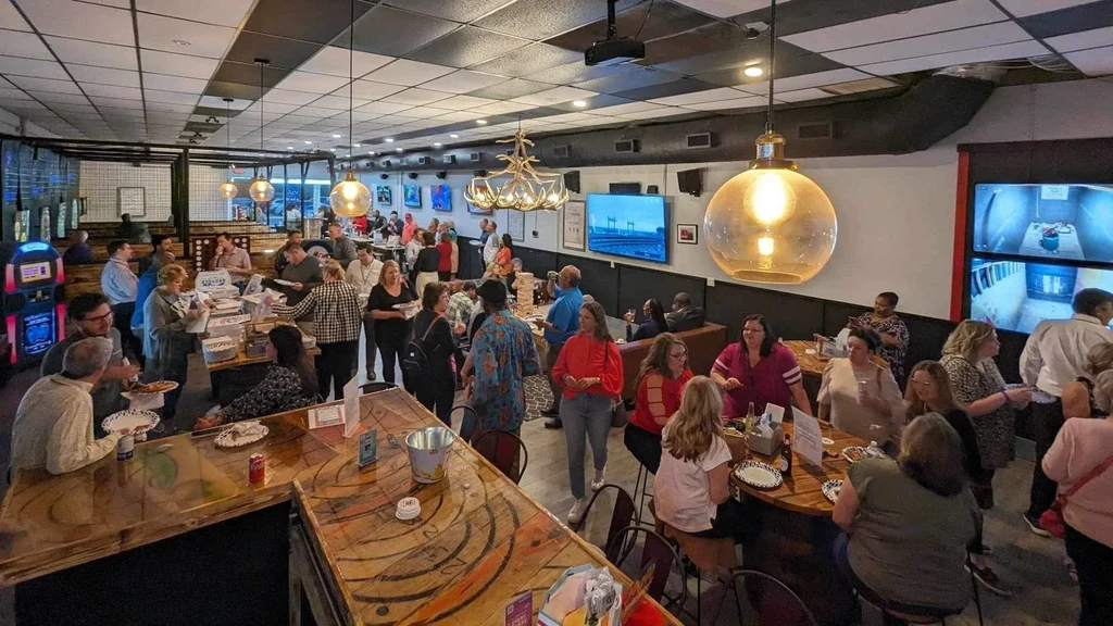 Bustling industrial bar and restaurant with patrons and food.