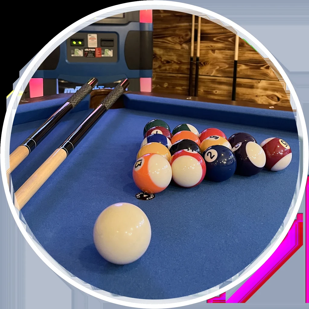 Blue felt pool table with racked billiard balls, cue ball, and cues.