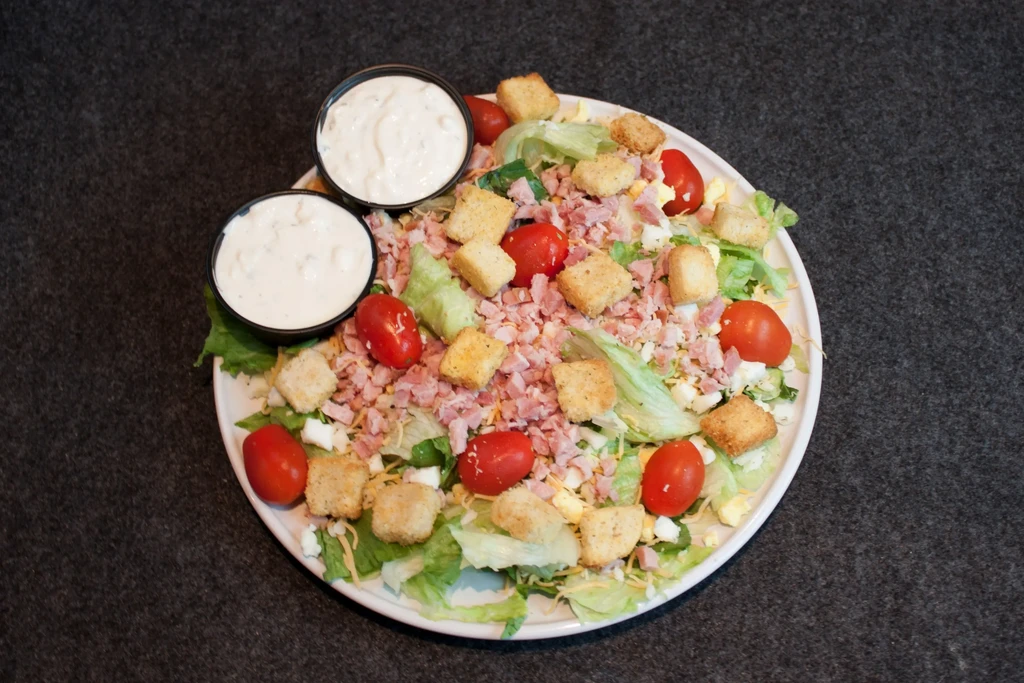 Mixed green salad with ham, cheese, tomatoes, croutons, and egg.