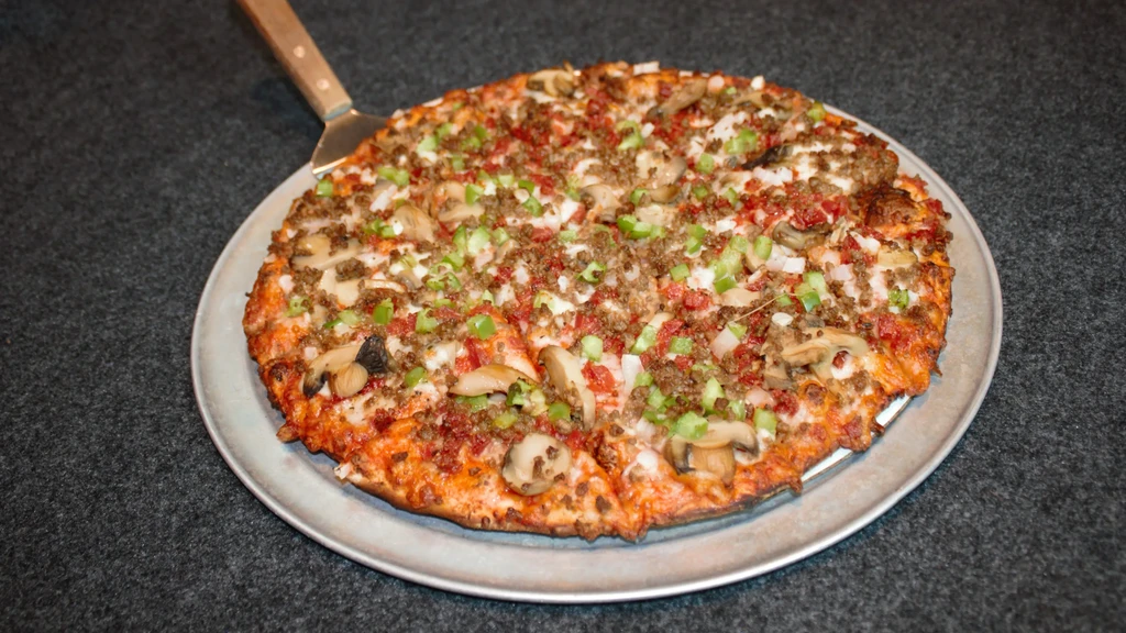 Round pizza topped with meat, green peppers, onions, and mushrooms.