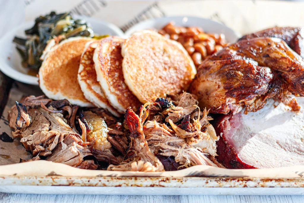 Hearty barbecue meal: pancakes, pulled pork, poultry, brisket, greens, and beans.