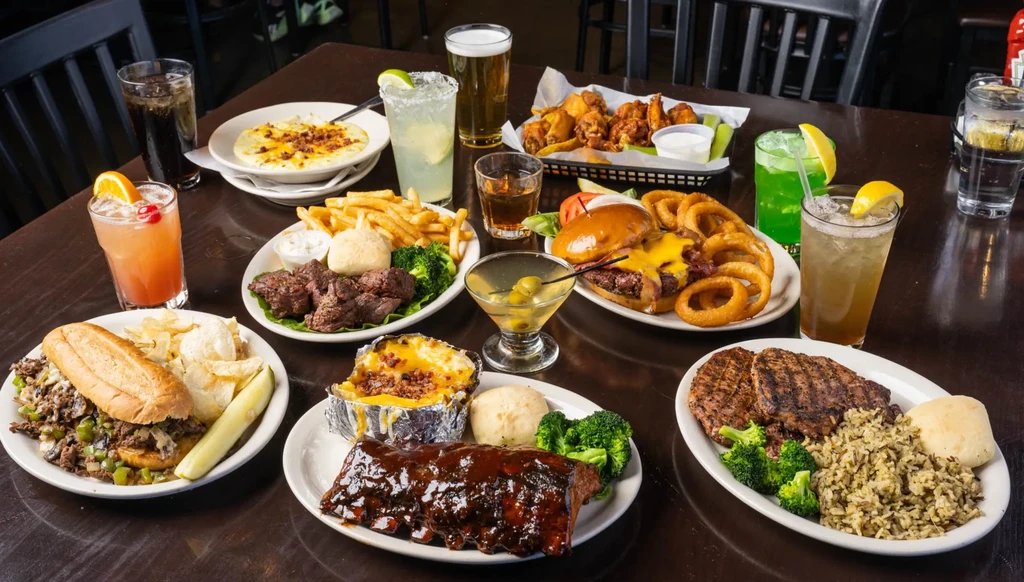 A plentiful spread of various food and drinks on a dark wooden table.