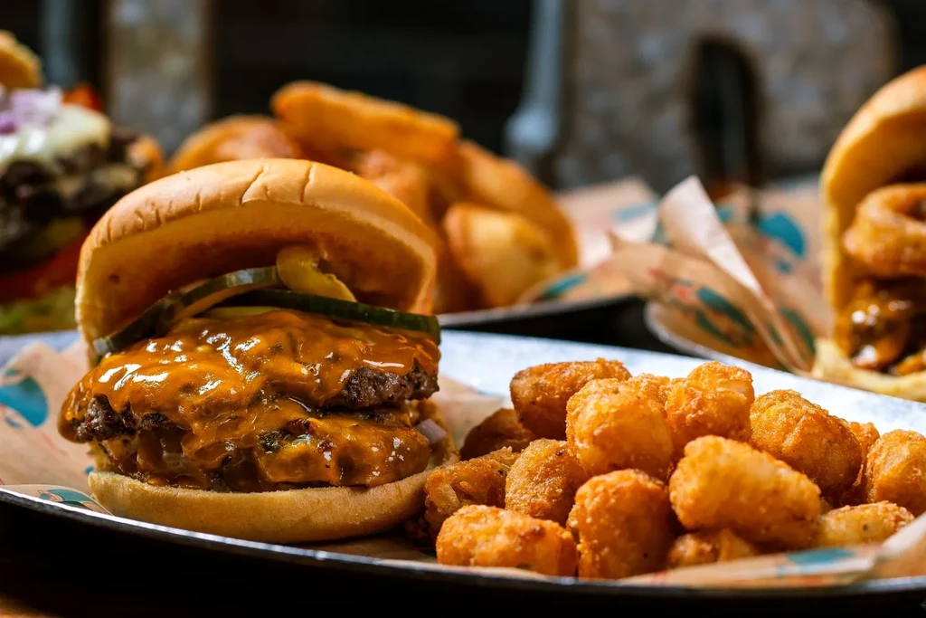 Double-patty cheeseburger with melted cheese, pickles, and a side of tater tots.