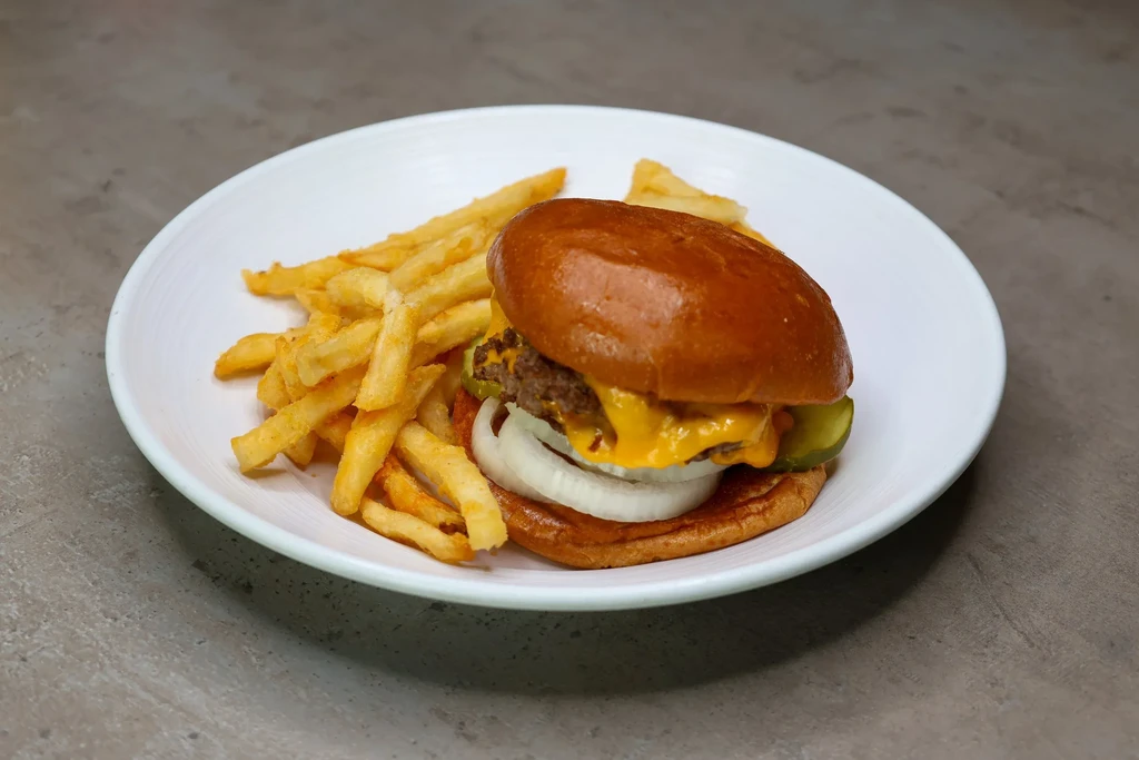 Cheeseburger with melted cheese, pickles, onions, and golden french fries.