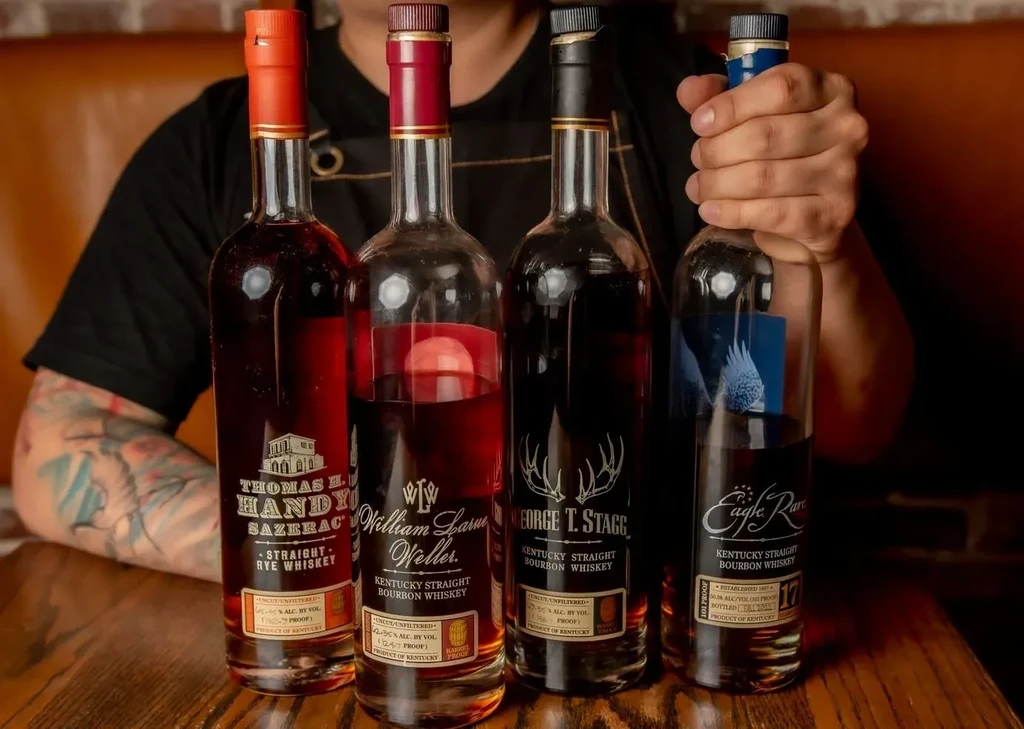 Thomas Handy, Weller, Stagg, Eagle Rare whiskey bottles, hand holding one.