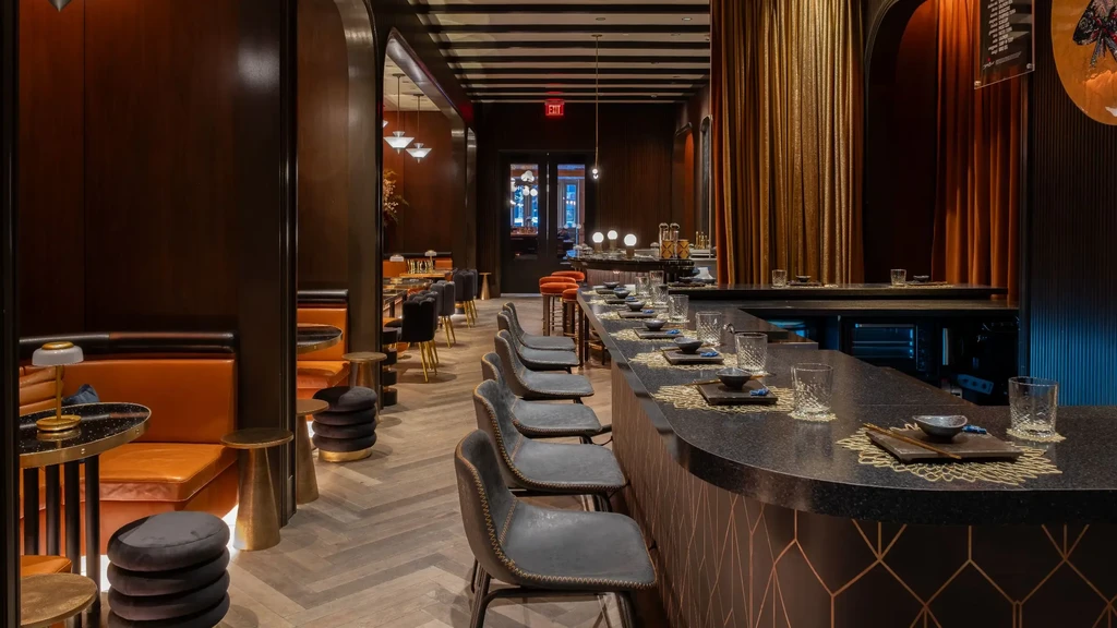 Empty, elegant restaurant interior with a geometric bar and leather booths.