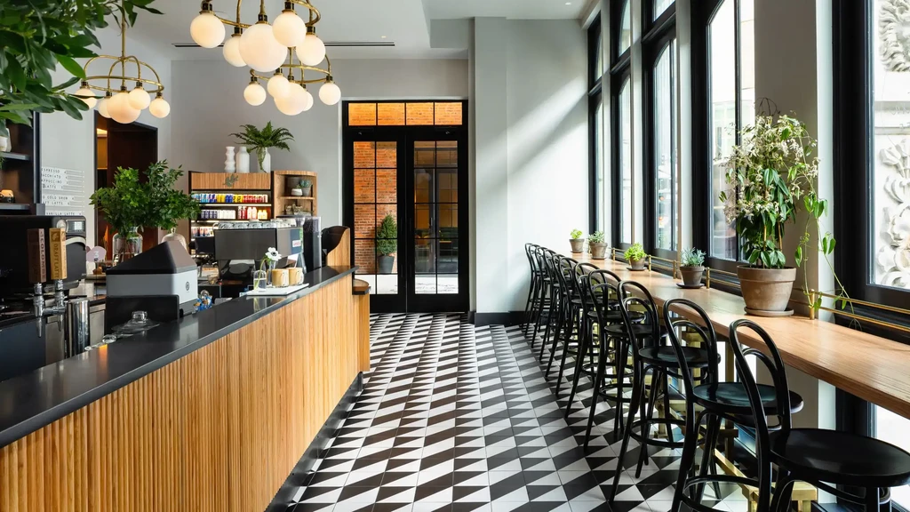Modern cafe interior with a sleek counter, geometric floor, and brass chandeliers.