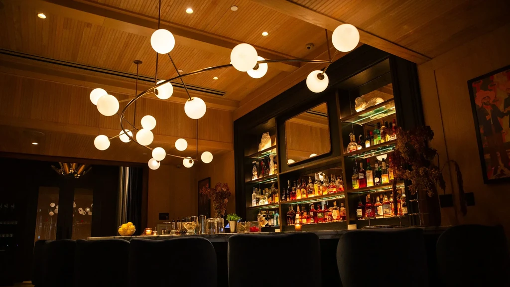 Sophisticated bar interior with well-stocked counter, chandelier, and wood ceiling.
