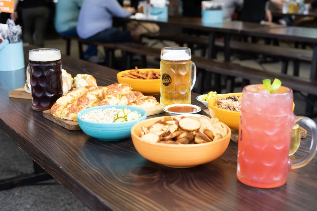 German beers, cocktail, flatbread, and food on a rustic communal table.