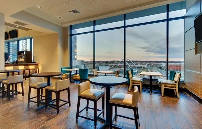 Modern restaurant interior with city skyline, bridge view, and varied seating.