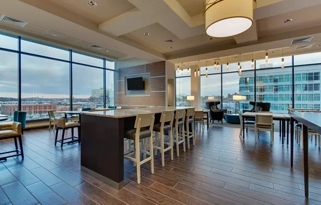 Modern interior room with long counter, varied seating, urban view.