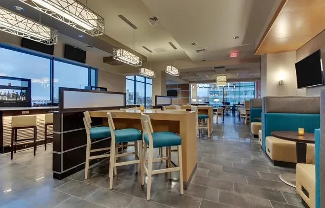 Empty modern restaurant with bar, high-tops, and booth seating.