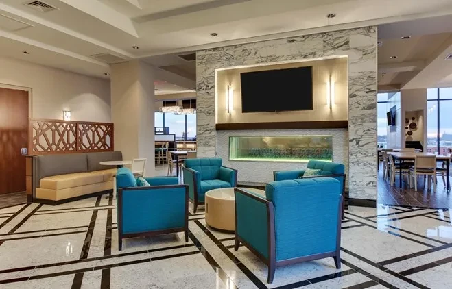 Modern interior with teal lounge chairs, booth, and geometric marble floor.