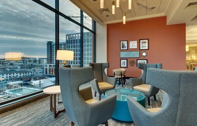 Modern lounge with armchairs, art wall, and panoramic city view.