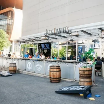 Jack Daniel's Tavern patio with outdoor seating, patrons, and cornhole games.