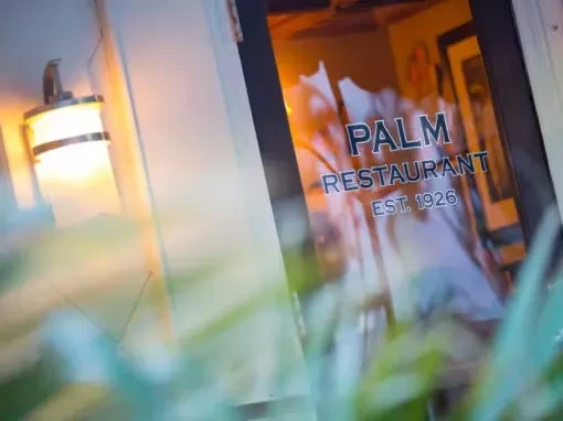 Palm Restaurant entrance at dusk with 'EST. 1926' on glass.