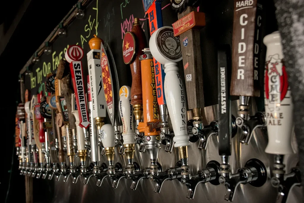 Close-up of a long row of diverse beer and cider tap handles.
