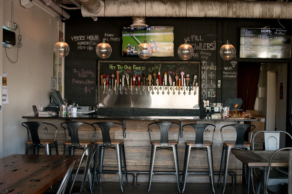 An empty craft beer bar with rustic counter, taps, and menus.