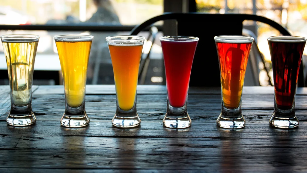 Six colorful drinks in glasses on a rustic wooden table.