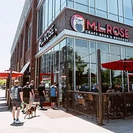 M. L. Rose restaurant exterior with patio, people, and red umbrellas.