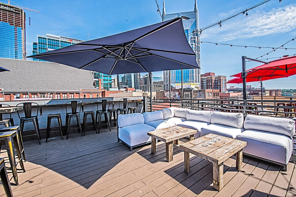 Rooftop restaurant patio with diverse seating, umbrellas, and city skyline.