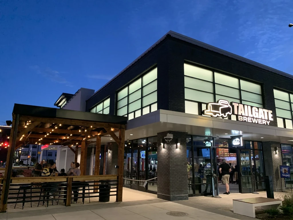 Modern Tailgate Brewery building exterior at dusk with lively patio.