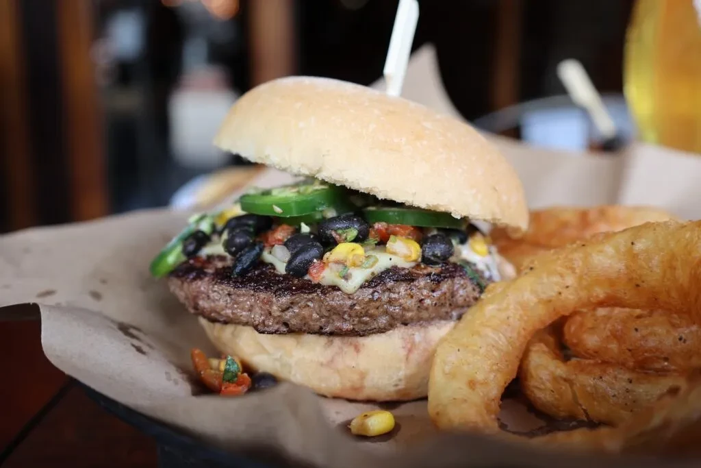 Burger with cheese, jalapeños, corn, beans, and curly fries.