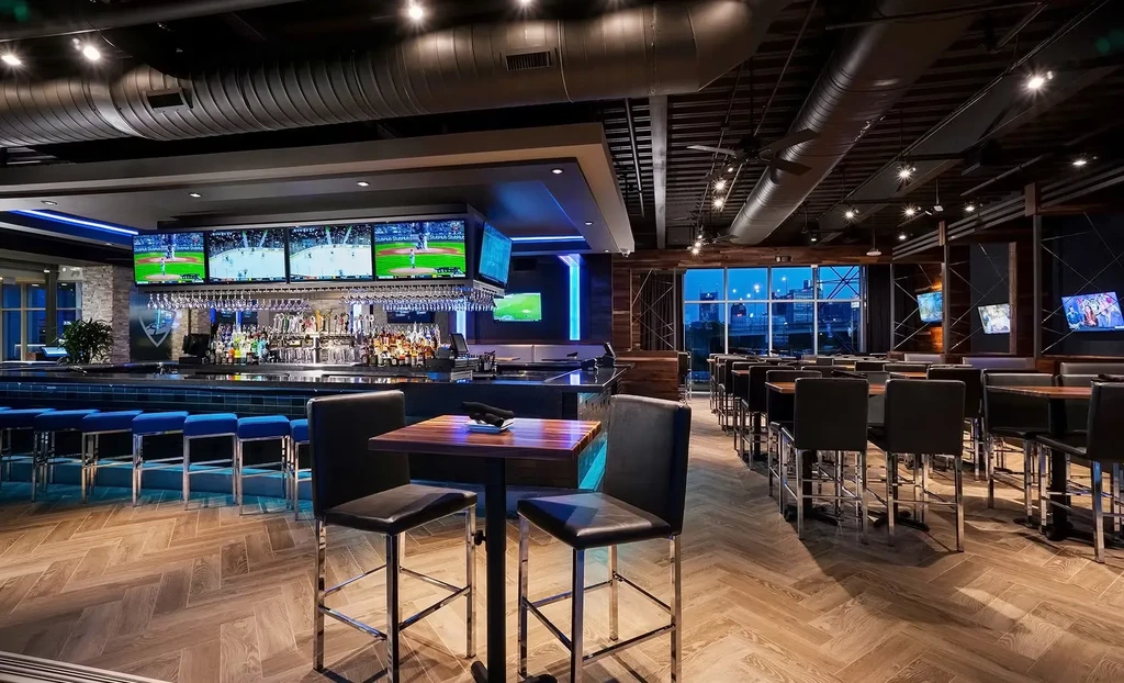Empty, modern sports bar interior with TVs, bar, and high-top tables.